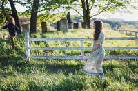 A mother and child move through a sunlit field, captured in an unposed family photo that reflects connection, movement, and everyday beauty.
