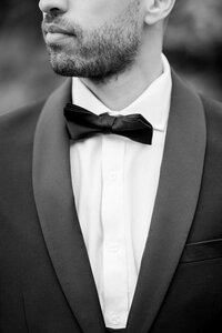 Sophisticated groom adjusts his bow tie, captured by a Bay Area Wedding Photographer, highlighting refined style.