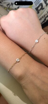 Gold and silver mother-daughter initial bracelets with dainty chains.