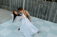 Bride and groom sharing a playful dip during their first dance on a checkerboard floor at a Utah wedding.