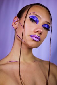 Woman with bright purple makeup and hair pulled back