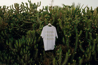 Dance studio branding on a white t-shirt hanging on pine tree branches.