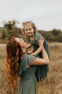 mom holding her little girl in the air