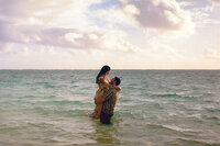 engaged couple embrace in the water on Oahu at sunrise