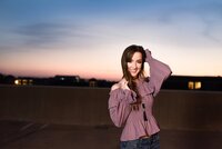 Senior at MTSU campus wearing purple shirt standing on parking garage at sunset