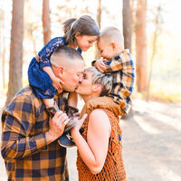 family in navy and gold plaid kissing with kids on their shoulders