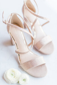close up photo of the bridal shoes with flower petals by  a wedding photographer in Colorado
