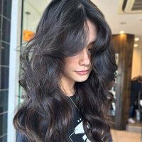 Brunette hair styled in voluminous waves with glossy highlights, captured in a modern hair studio.