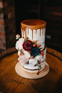 beautiful cake with florals and caramel drizzle on wine keg