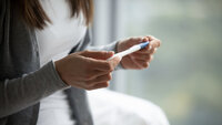 Woman standing near a window talking on a cellular phone.