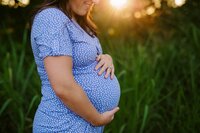 Pregnant mom hugs belly in a Memphis field during her maternity photo session by Jen Howell Photography.