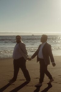 Two Grooms walking hand in hand on the beach 