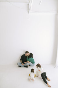 child standing and smiling with parents and baby