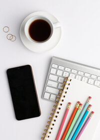 cell phone, keyboard, coffee, and colored pens on white background