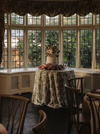 "Beautifully decorated wedding cake with intricate floral designs and elegant tiers, showcased on a table adorned with candles and greenery."