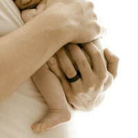 fathers hands holding tiny newborn