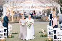 bride smiling next to mother of the bride holding white flowers