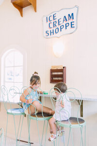 Two little kids sitting on barstools at an ice cream shop