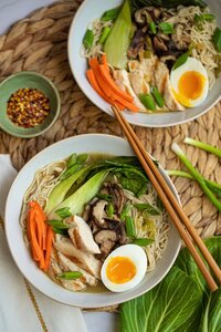 two bowls of pho on a wicker placemat