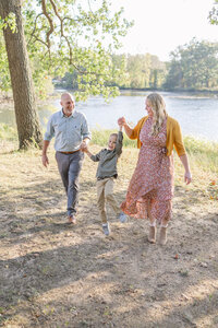 a family of 3 near a grassy field at golden hour