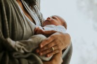 A woman holds a newborn baby.