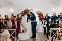 A couple kisses while friends and family cheer