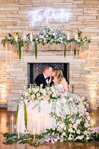 Bride and Groom share a kiss at their sweetheart table at Canyonwood Ridge