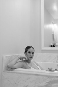 black and white photo of bride sitting in bathtub