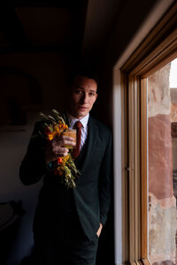 Groom holding the wedding bouquet during a Utah wedding, photographed by Lamblight Photography