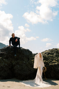 groom sitting on boulder, bride standing nearby, destination wedding, elopement