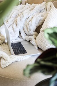 Laptop sobre sofá y cobijas.