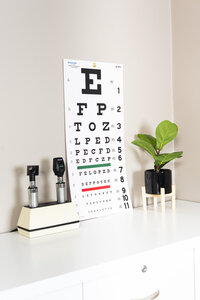 an eye chart, plant, and eye exam tools on top of a cabinet