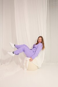 studiomaiju istuu tuolilla jalat ylhäällä ja nauraa