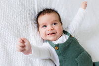 A small baby smiling and reaching up