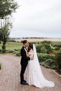 Bride and Groom share kiss with McLaren vineyards for backdrop.