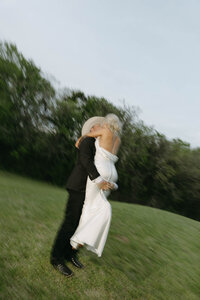 Bride twirling on open field in soft natural light, symbolizing romantic elegance and joy.