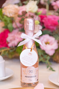 A bottle of Prosecco favor on a table at a baby shower. 