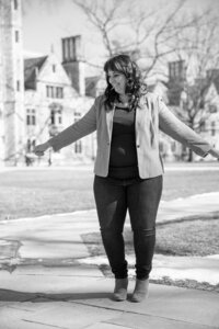 black and white photo of woman with arms out at university of michigan law quad