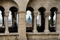 Stone archways framing a panoramic view of Budapest with St. Stephen’s Basilica visible in the distance.