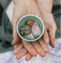 Hands holding crystals in a turquoise bowl