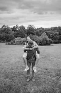 A person holding their partner on their back as they walk through a field