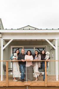 family standing on deck in front of house