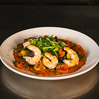 White prawns with fresno sofrito, roasted fingerlings, snap peas, black kale, chorizo, smoked tomato bleu cheese sauce Max Dales Steak and Chop House Restaurant