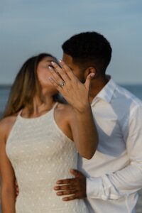 Couple embraces during sunset on the rocks at Jetty Park Beach in Port Canaveral, celebrating their engagement — photographed by an Orlando Proposal Photographer.