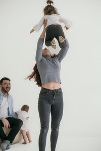 Mom throws dauther in the air while dad holds baby girl.