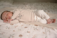 Newborn ligt op zijn zij te slapen met zijn voetjes over elkaar tijdens een newbornshoot