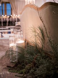 Tall pillar candles and dried grass behind a vintage sofa