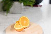 Fresh cut oranges on a wood platter on a kitchen counter