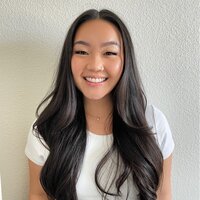 asian young woman with long wavy hair, wearing a white short-sleeved top, sliming and looking directly at the camera