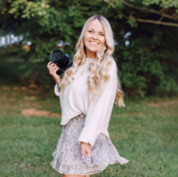 girl smiling in front of white wall in cozy sweater